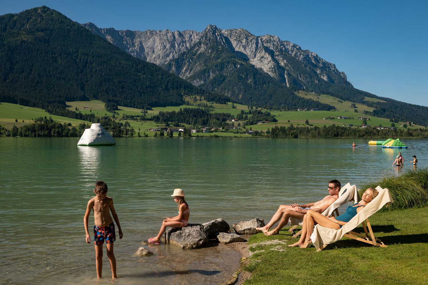 Badeplatz am Walchsee im Kaiserwinkl in Tirol mit Liegewiese und Bergblick