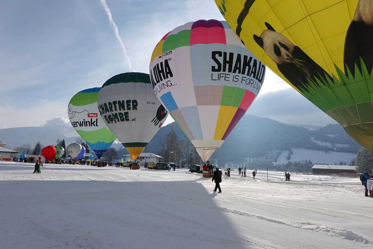 Heißluftballone beim Alpin Ballooning im Kaiserwinkl in Tirol auf verschneiter Fläche mit Bergblick